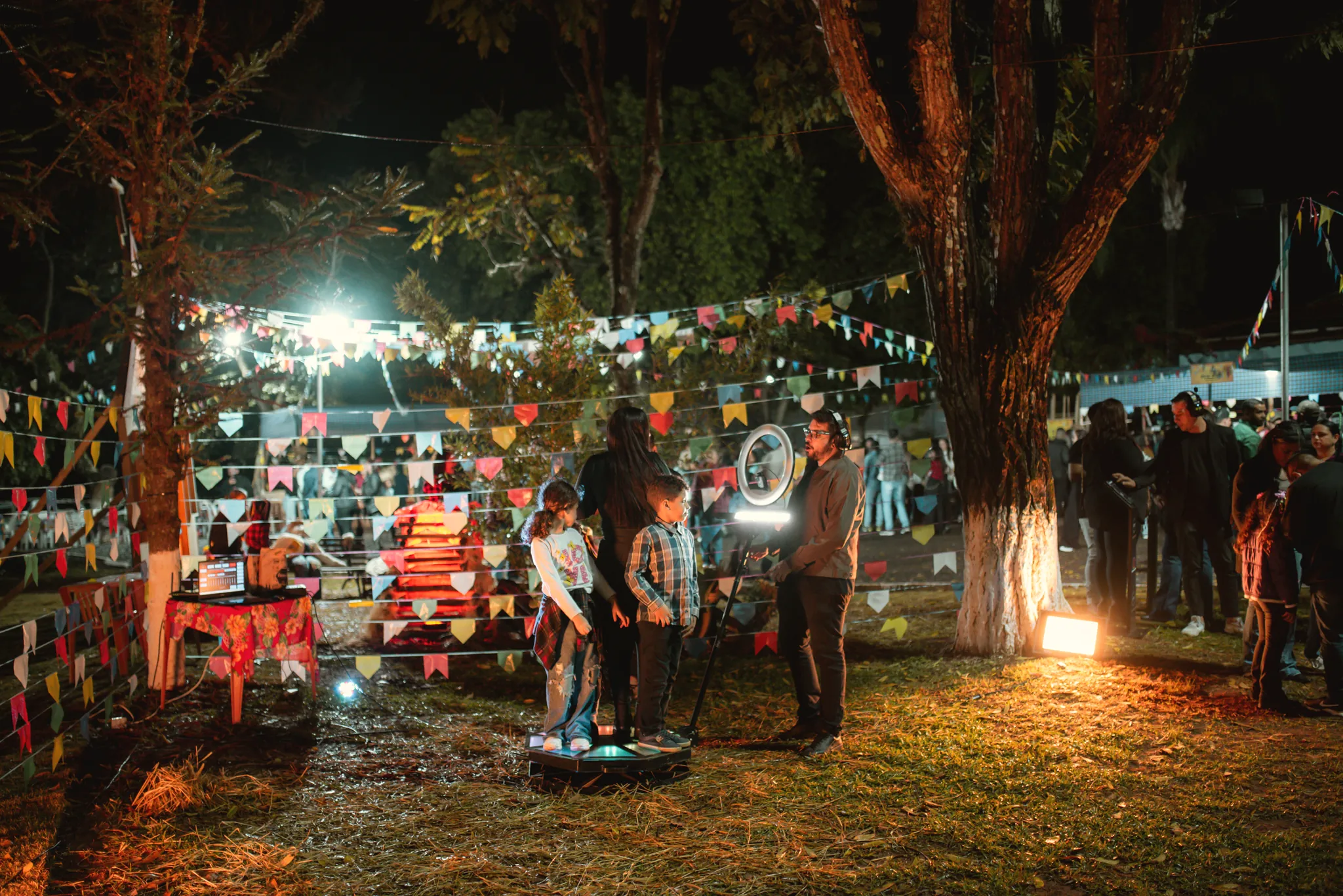 Festa junina à noite, com bandeirinhas e luzes entre as árvores