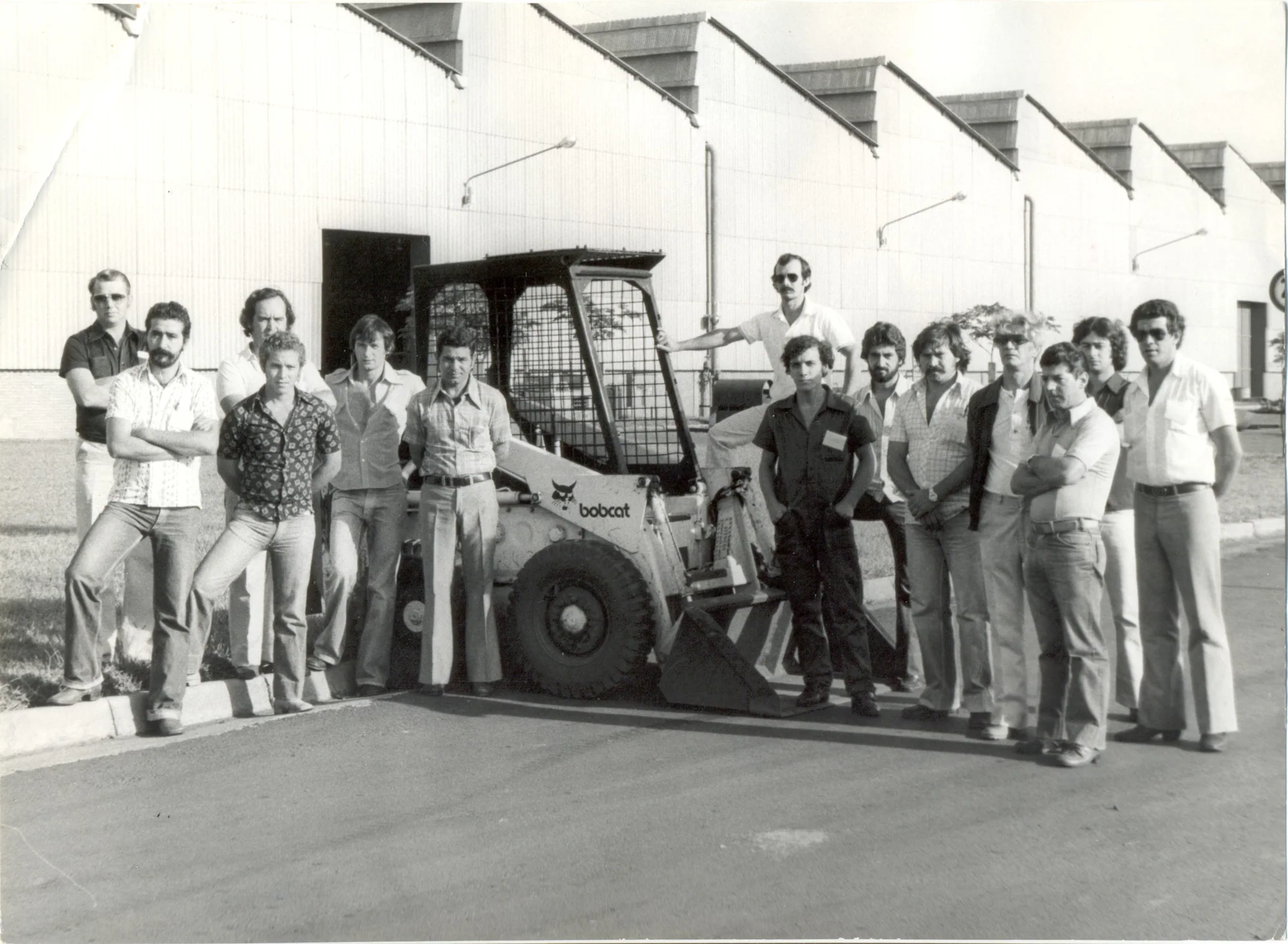 Equipe da fábrica posando ao lado de uma máquina