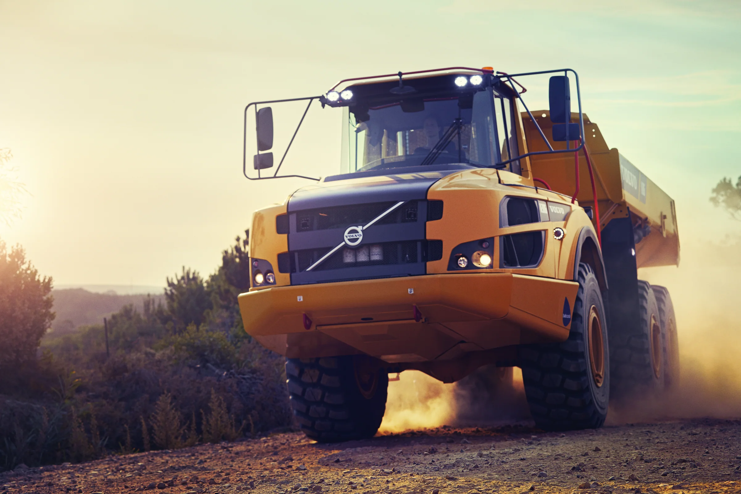 Caminhão articulado Volvo em movimento numa estrada de terra ao entardecer